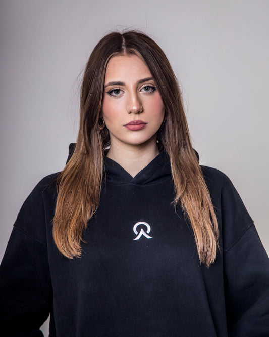 Woman wearing a black hoodie with a logo on a gray background